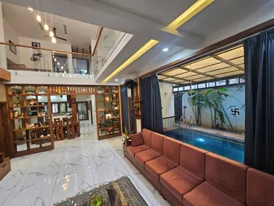 a living room with a couch and a swimming pool at Dreams Premium Villa in Kozhikode