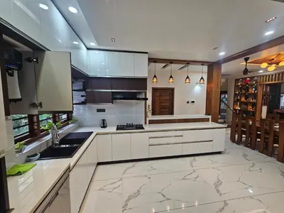 a large kitchen with white cabinets and a sink at Dreams Premium Villa in Kozhikode