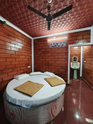 a bedroom with a large bed in a room with a sink at Nasmat Resort in Masinagudi