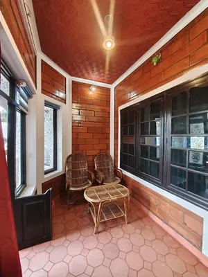 a screened in porch with two chairs and a table at Nasmat Resort in Masinagudi