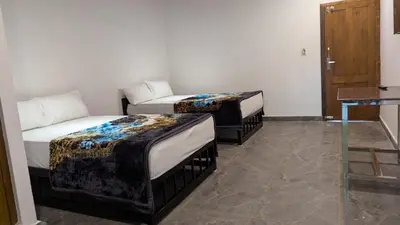 two beds in a room with a room with a table at Soul Stay in Munnar