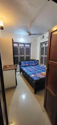 a bedroom with a bed and a table and two windows at Periyar Heritage in Kotamangalam