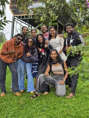 a group of people posing for a picture in the grass at Woodshade resort in Wayanad