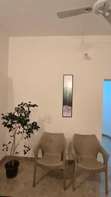 two chairs and a table in a room with a plant at The Horalahalli House in Mysore