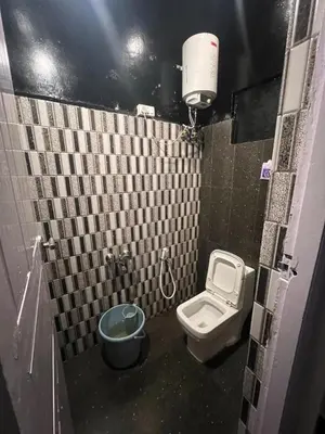 a small bathroom with a toilet and a bucket at The Groot in Ooty