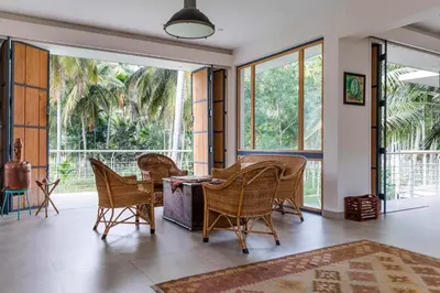 a living room with a table and chairs and windows at Spacious 3BR Daveys Townhouse with Private Lawn Pet Friendly and Complimentary Breakfast in Mysore