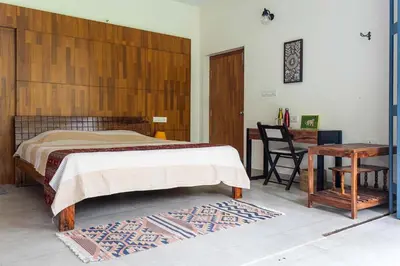 a bedroom with a bed with a wooden headboard and a desk at Spacious 3BR Daveys Townhouse with Private Lawn Pet Friendly and Complimentary Breakfast in Mysore