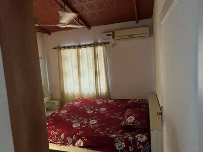 a bedroom with a bed with a red comforter and a window at Cityscape Residence and Homestay Tirupur in Tiruppūr