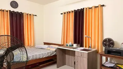 a bedroom with a bed with orange curtains and a desk at Casa Areca in Cheruthuruthi