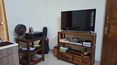 a living room with a flat screen tv and a book shelf at Casa Areca in Cheruthuruthi