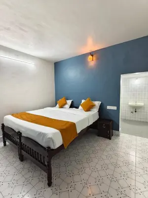 a bedroom with a large bed with a blue wall at Kalanja Greens Nilagiri Villa in Ooty
