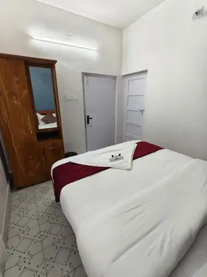 a bedroom with a large white bed and a door at Kalanja Greens Nilagiri Villa in Ooty