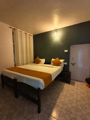a bedroom with a large bed with orange pillows at Kalanja Greens Nilagiri Villa in Ooty