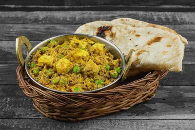 a bowl of chicken and rice in a basket with a slice of bread at Palette Nirvana Signature Apartment by CheckIn, Coimbatore in Coimbatore
