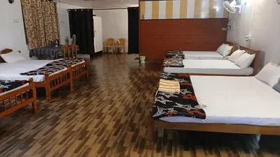 three beds in a room with wooden floors at BeingWild Resort in Masinagudi