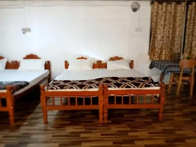 a bedroom with two beds and two chairs at BeingWild Resort in Masinagudi