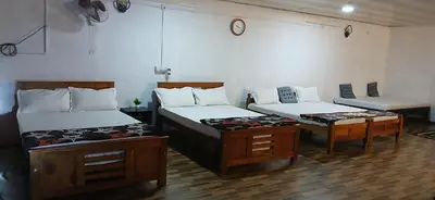 a room with two beds and a table at BeingWild Resort in Masinagudi