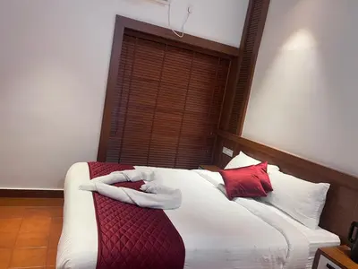 a bedroom with a bed with red and white pillows at Haveninn in Athirappilly