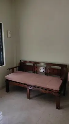 a large wooden bench sitting in a room at Green Valley stay in Pattāmbi