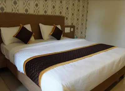 a bedroom with a large bed with white sheets and pillows at Hotel Janani Mansion in Mysore