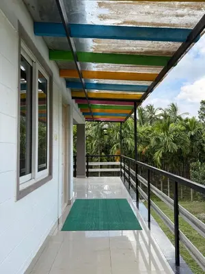 a balcony of a house with awning and a green rug at Murthi's Farm House in Coimbatore