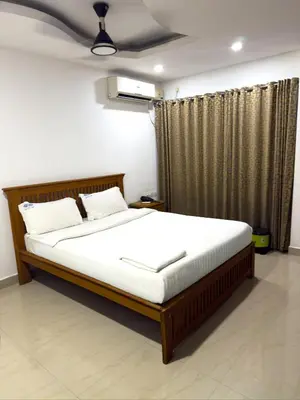a bedroom with a large bed with white sheets at Sathya Inn Guruvayur in Trichūr