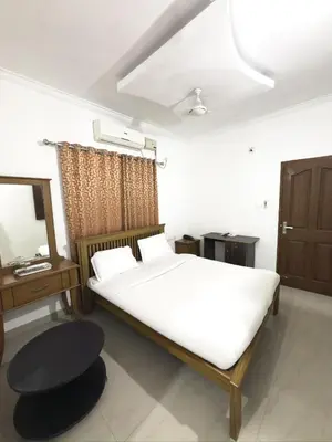 a bedroom with a bed and a table and a mirror at Sathya Inn Guruvayur in Trichūr
