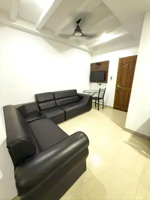 a living room with a black leather couch and a table at Sathya Inn Guruvayur in Trichūr