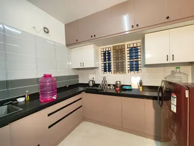 a kitchen with white cabinets and black counter tops at Namasvi 2Bedroom AC House in Narasimharaja Puram