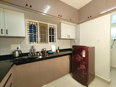 a kitchen with white cabinets and a brown refrigerator at Namasvi 2Bedroom AC House in Narasimharaja Puram