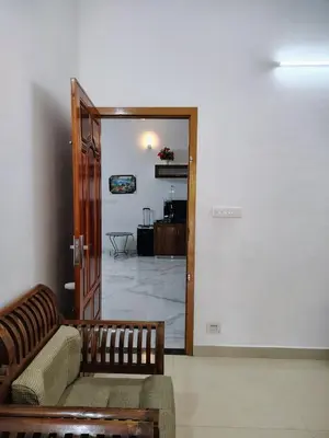 a living room with a couch and a open door at Maliyeckal Homes in Viripara