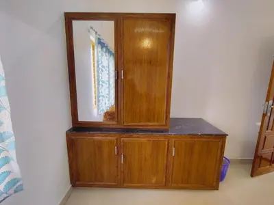 a wooden cabinet with a mirror on a wall at Maliyeckal Homes in Viripara