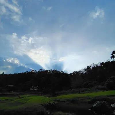 a rainbow in the sky over a field with a river at Maliyeckal Homes in Viripara