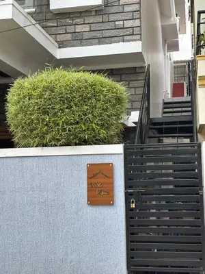 a sign on the side of a building with bushes at Villa Vista in Mysore