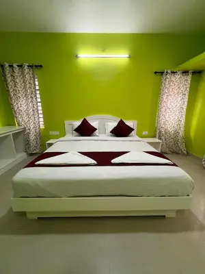 a bedroom with a large bed with green walls at Essar Cottage in Ooty