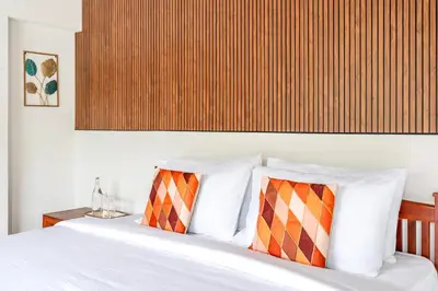 a bed with white sheets and orange and white pillows at Riverstone Haven in Kotagiri