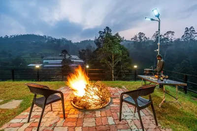 a fire pit with two chairs and a table at Riverstone Haven in Kotagiri