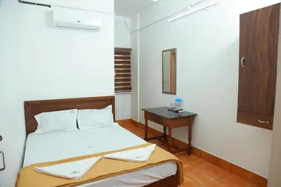 a small bedroom with a bed and a table at Vinayaka Tourist Home in Kozhikode
