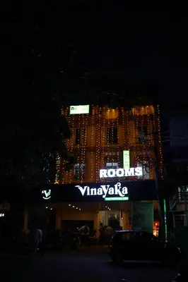 a building with a sign on the side of it at night at Vinayaka Tourist Home in Kozhikode