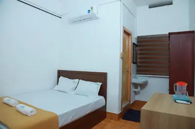 a bedroom with a bed and a desk and a sink at Vinayaka Tourist Home in Kozhikode