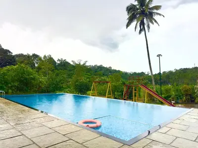 an empty swimming pool with a playground and a palm tree at Karlad Lake Palace Waterfront Resort by stayRAa in Tariyod