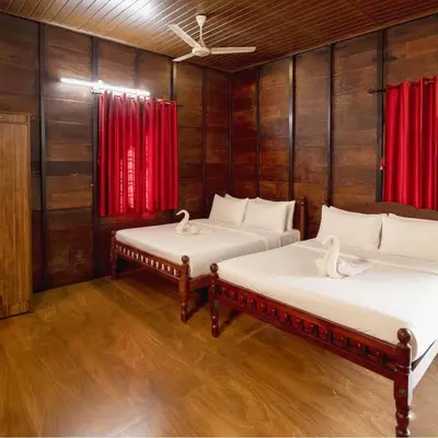 two beds in a room with red curtains at Karlad Lake Palace Waterfront Resort by stayRAa in Tariyod