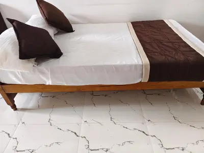 a bed sitting on top of a white tiled floor at krishna paadham in Guruvāyūr
