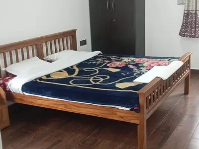a bed with a wooden frame with a blue blanket at Cherry Blossom in Kotagiri