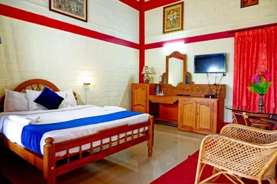 a bedroom with a bed and a desk and a television at Cybele Hill Resort in Kalpetta