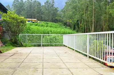 a white fence on a patio with a hill in the background at Brindavan Lake Resort in Munnar