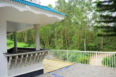 a white porch with a fence and trees at Brindavan Lake Resort in Munnar