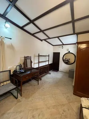 a living room with a table and a mirror at Balacalava Guest House in Coonoor