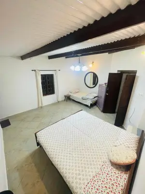 a room with a table and a couch and a mirror at Balacalava Guest House in Coonoor