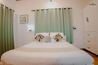 a bedroom with a large white bed with green curtains at Hope Horizon Luxury Villa By LexStays in Coonoor